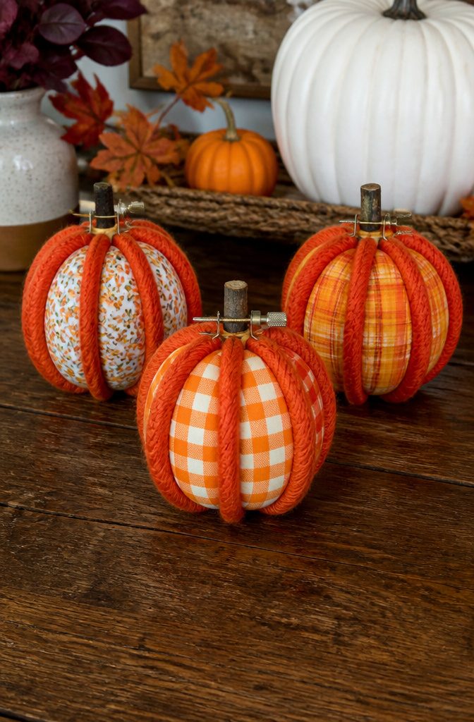 20 Fall Pumpkin Crafts to Make for Your Home in 2026 2 Three small embroidery hoop pumpkins wrapped in orange yarn.