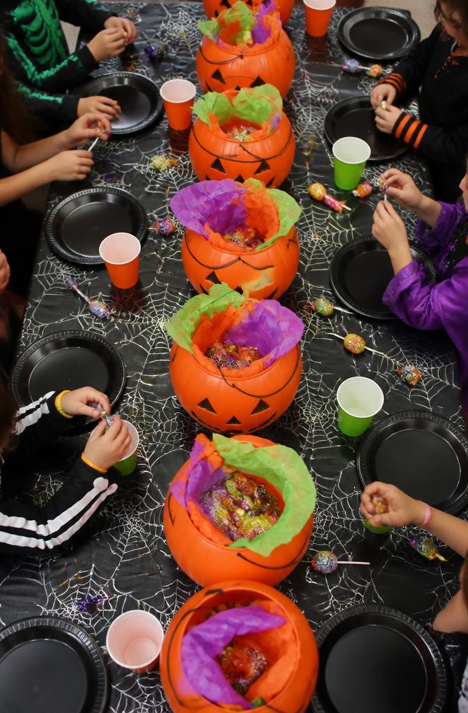 Large orange jack-o'-lantern plastic buckets arranged on a table.