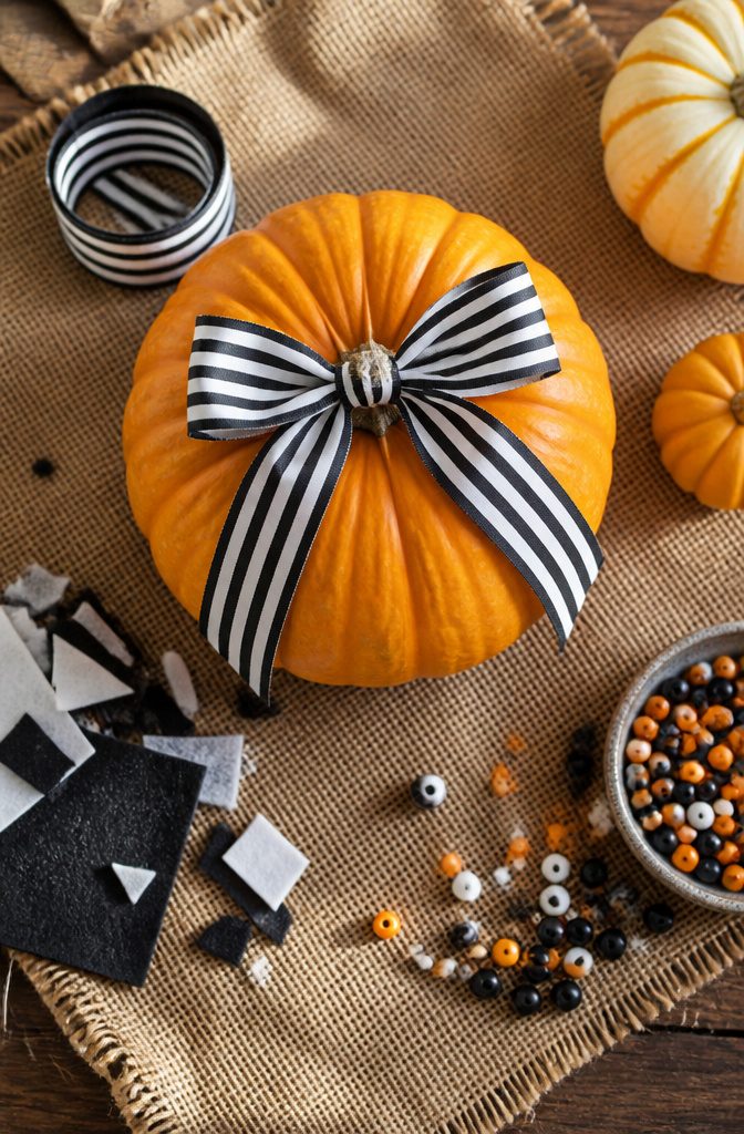 Pretty Painted Pumpkins: Ideas and Techniques for 2026 17 A pumpkin decorated with ribbon and felt elements.